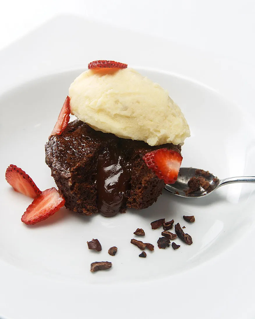 A plated chocolate fondant dessert with ice cream and fresh fruit